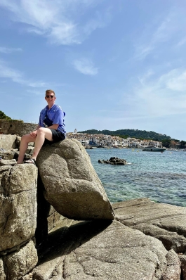 A photo of Dylan sitting on a rock overlooking the sea