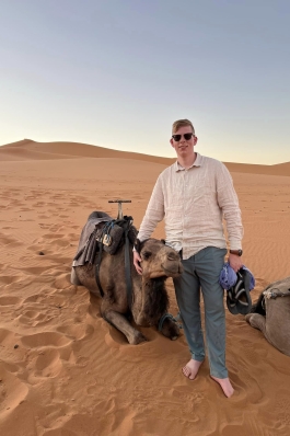 A photo of Dylan next to a camel in the Sahara