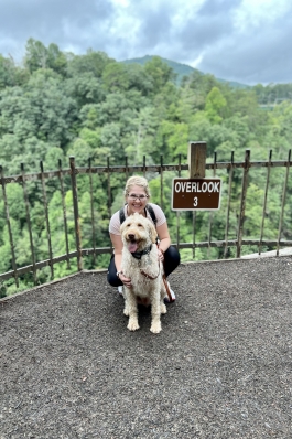 A photo of Anna and her dog at an overlook of a state park.