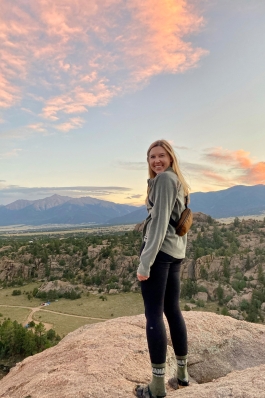 Allison Jones overlooking a rocky cliffside at the hillside and mountains beyond