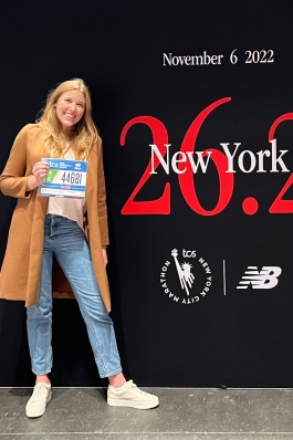 Allison Jones holding a racing number on a stage that says New York 26.2 November 6, 2022