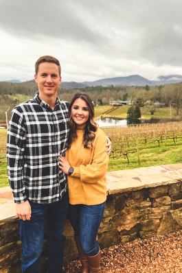 Ashlyn Johnson in front of a rock wall with fields, a lake and the Blue Ridge Mountains in the distance