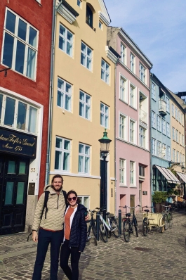 a couple standing in front of colorful buildings