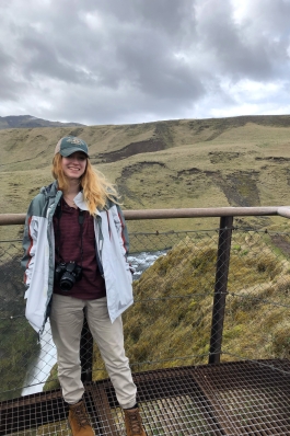 woman standing in front of grassy hills