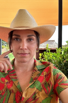 Laura Mier on a cowboy hat and shirt with red flowers