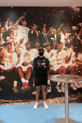 A picture of Andy in front of a pictured wall of Miami Heat players