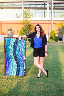 A photo of Jessica next to one of her art pieces.