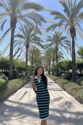 A photo of Tenzin surrounded by palm trees in Spain.