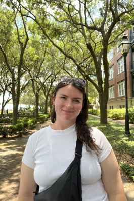 Eve smiling in front of trees on a trail.