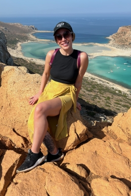Christie sitting on rocks near the water in Greece