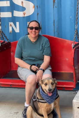 A photo of Lori and her dog sitting on a bench.