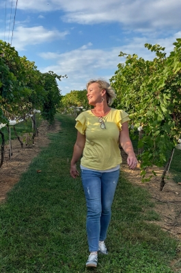 A photo of Missy walking through a path at a winery.